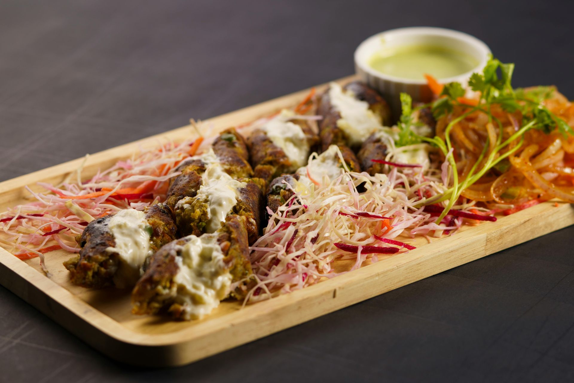 Grilled meat dish with sauce, vegetables on wooden platter.