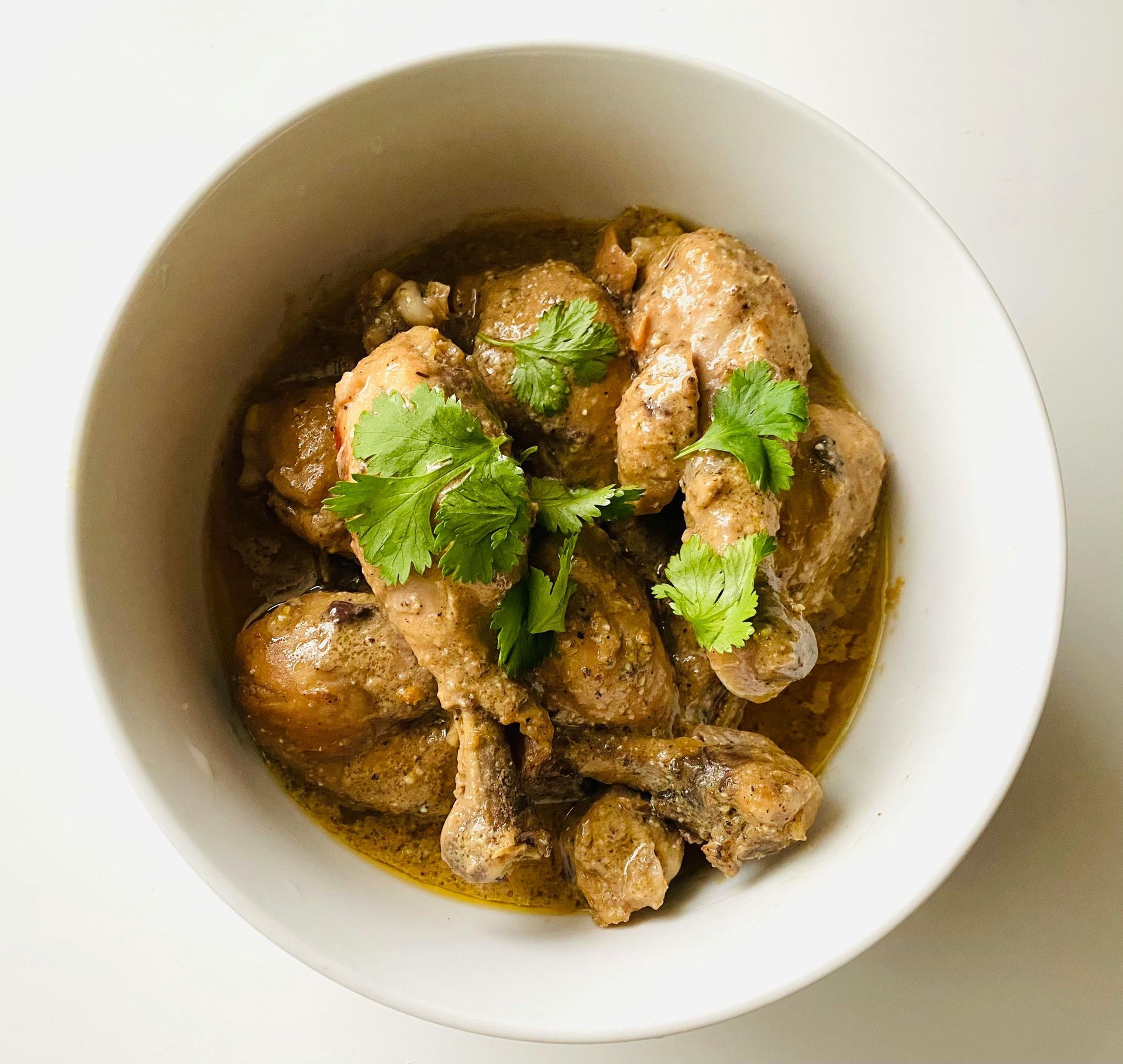 Chicken curry in a white bowl, garnished with cilantro.