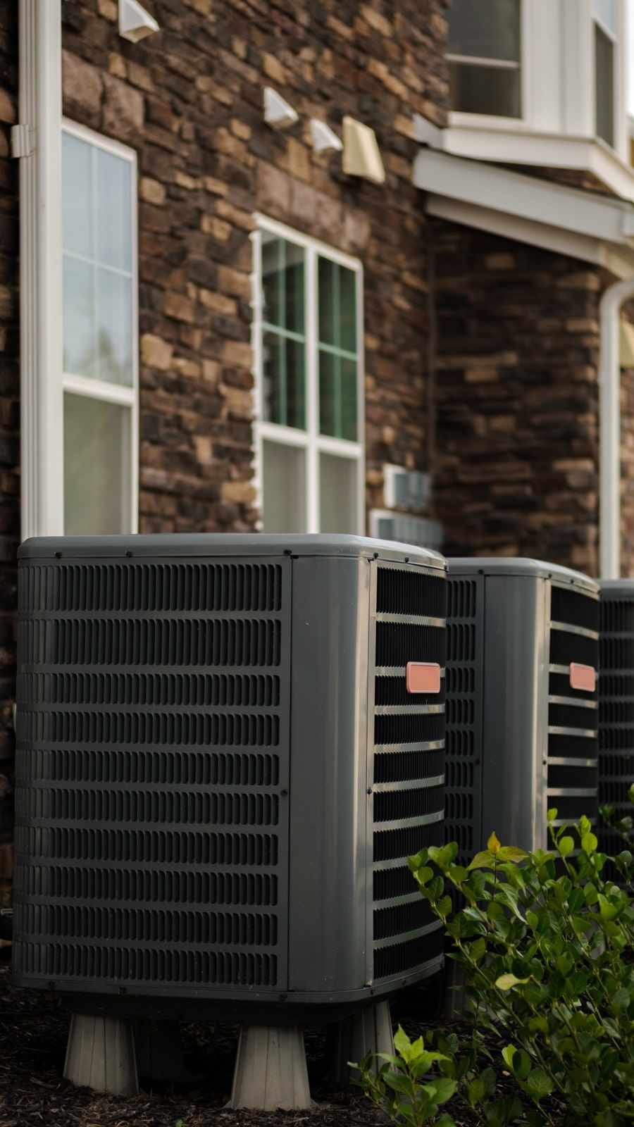 Two air conditioners are sitting outside of a brick building.