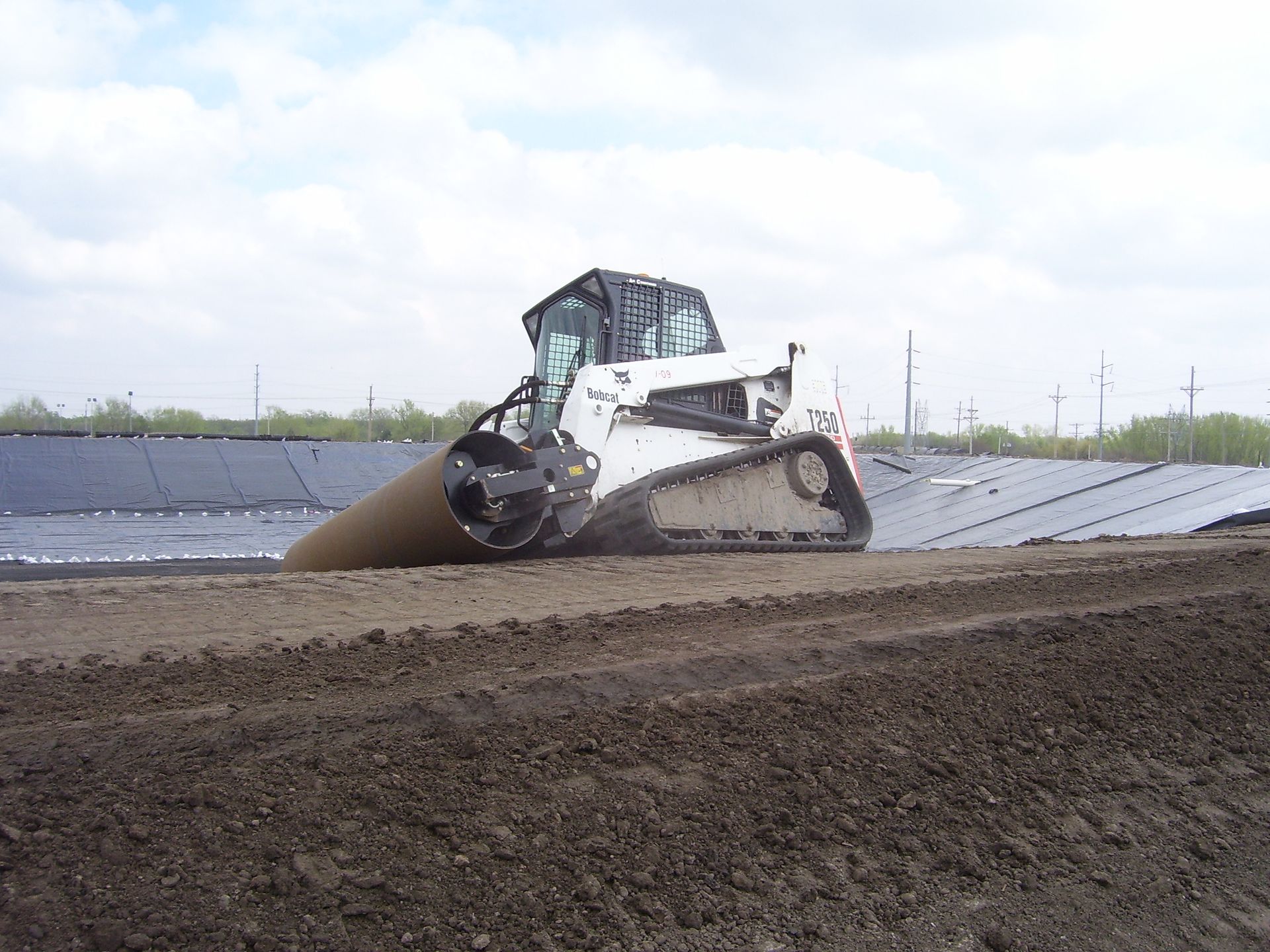 A construction worker is standing in front of a bulldozer at a construction site.