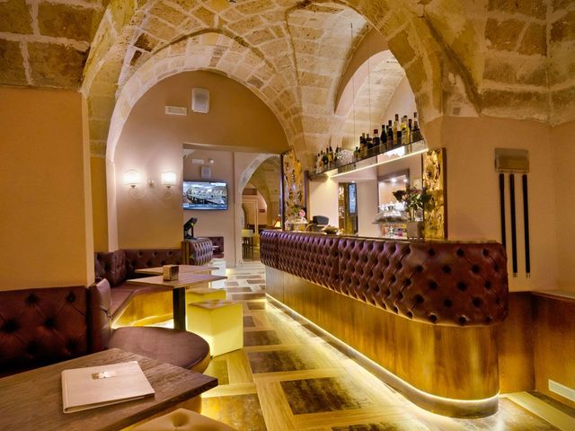 Interior of a bar with a curved leather bar front and arched stone ceiling; warm lighting.