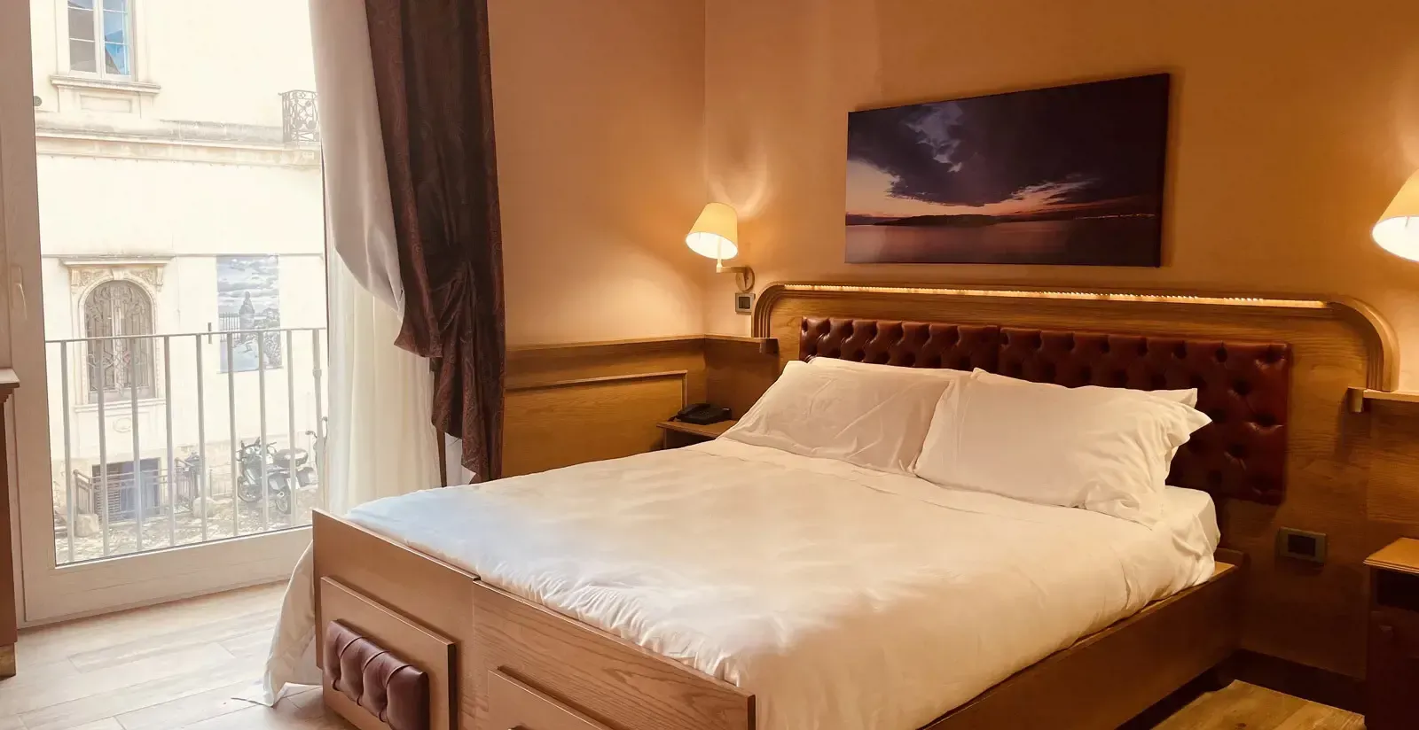 Camera da letto con letto grande, balcone e opere d'arte. Illuminazione calda nei toni del marrone e del bianco.