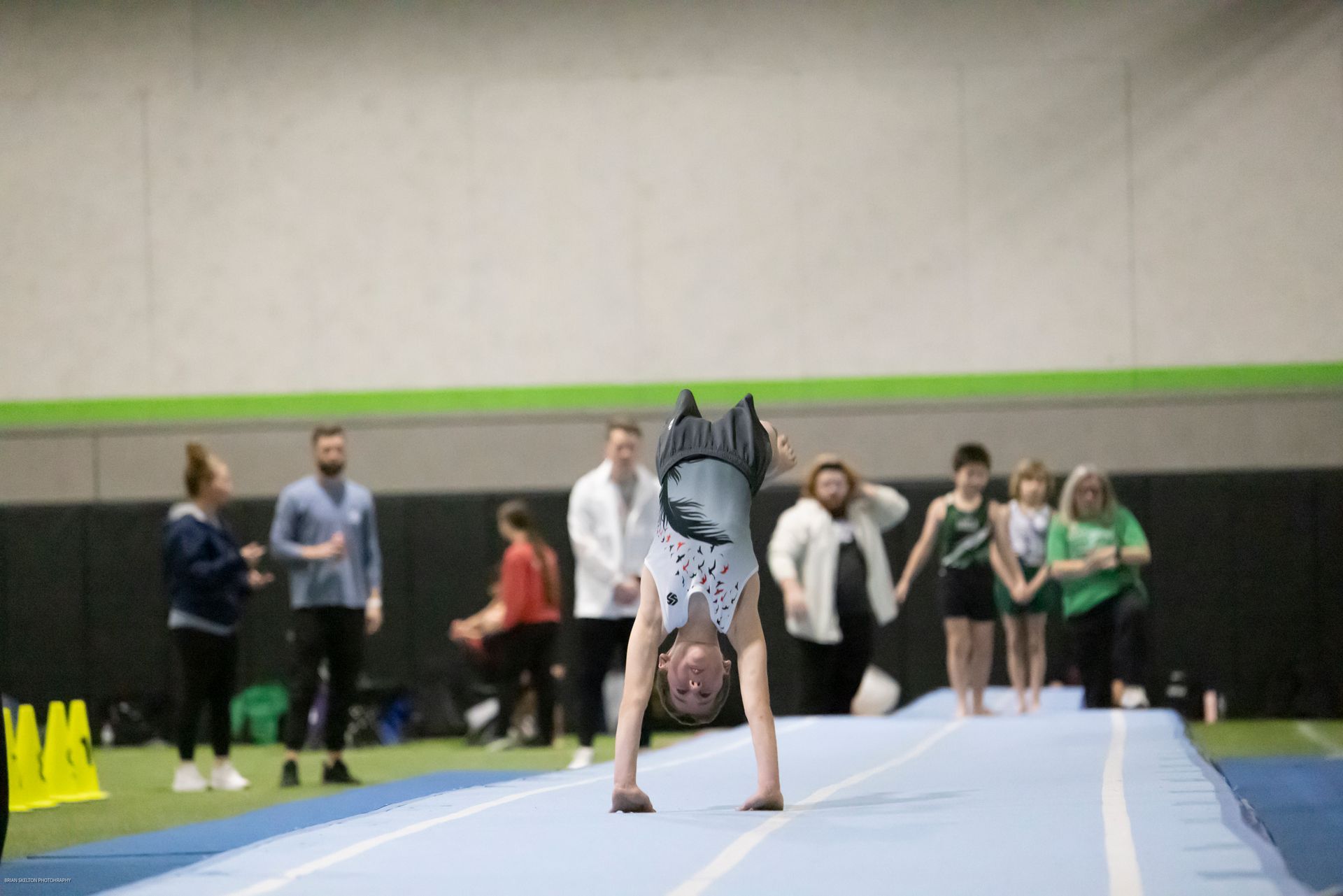 A woman is doing a handstand in a gym in front of a ford sign.