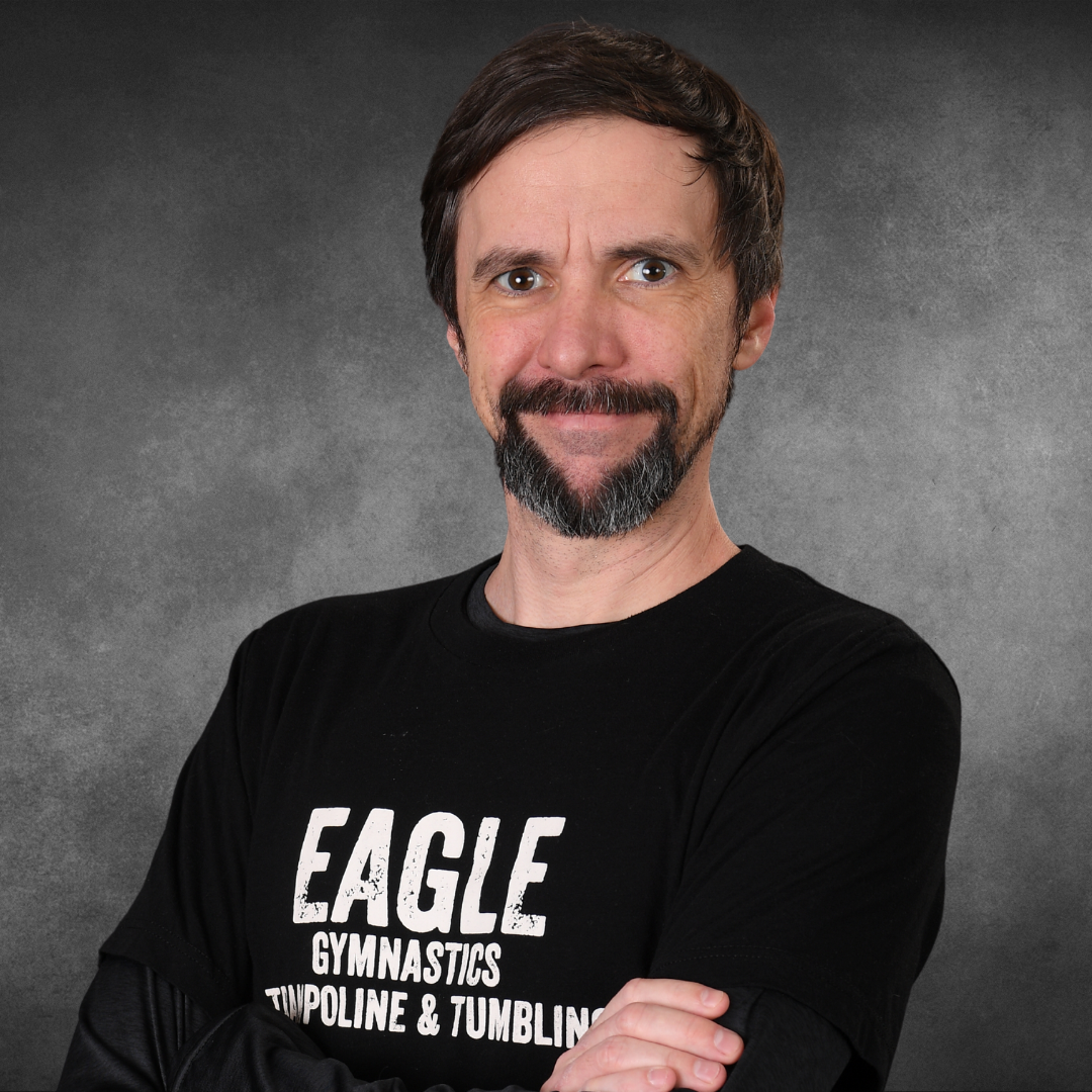 A man with a beard is wearing an eagle gymnastics shirt