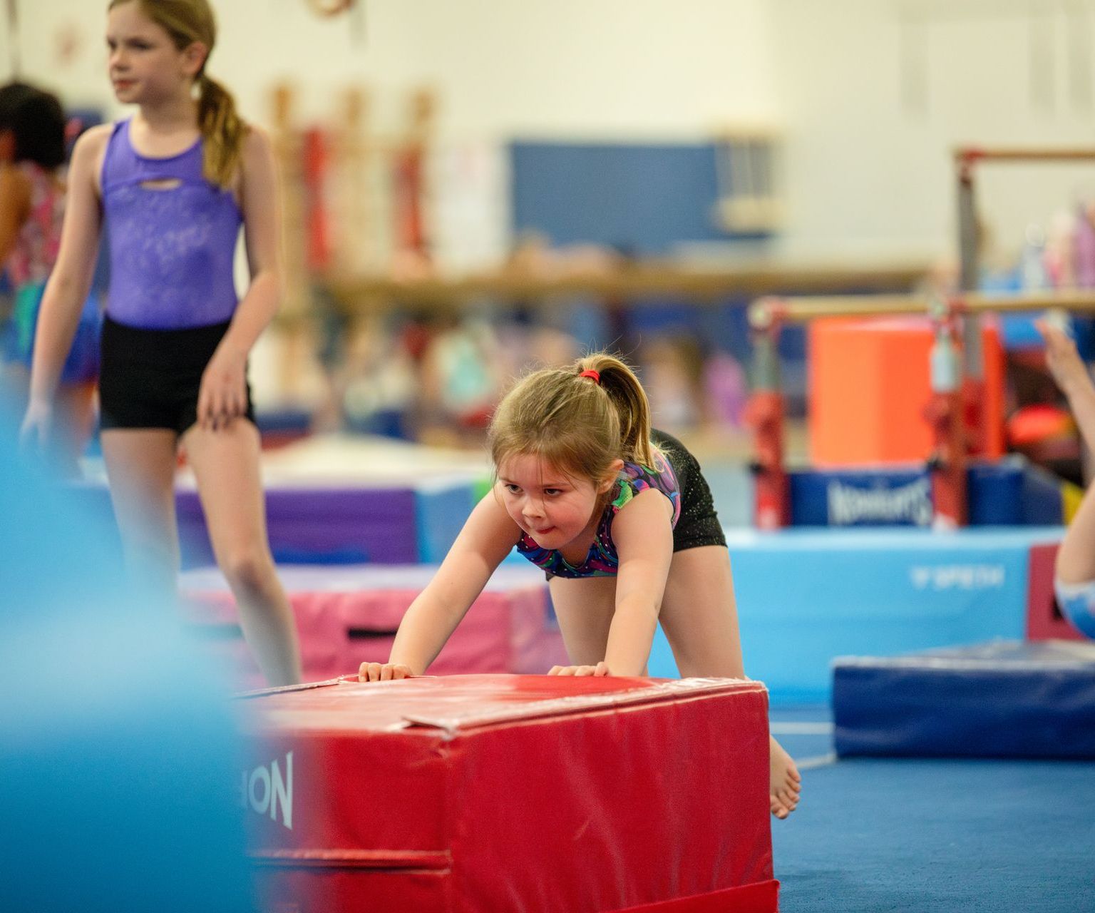 A young girl is doing a handstand on a blue mat