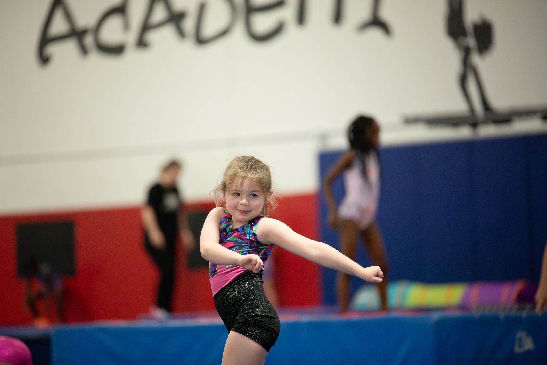 A young girl is doing a balance beam in a gym.