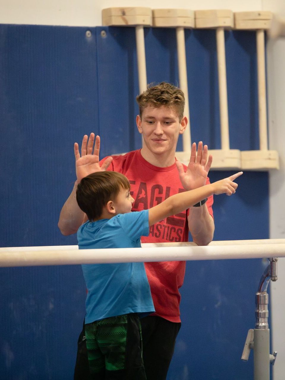 A man squatting next to a young boy wearing a shirt that says eagle