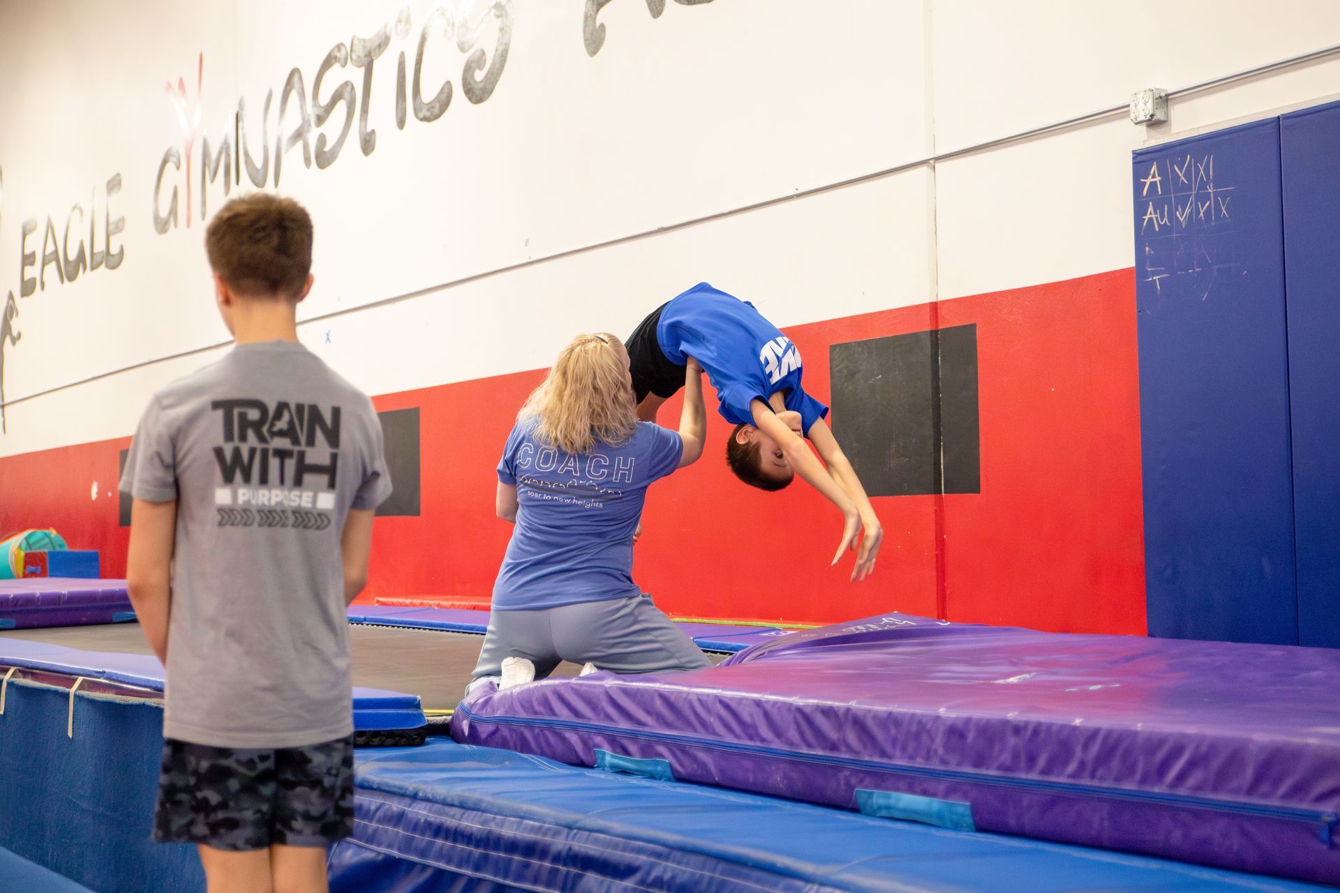 A young boy is doing a handstand on a trampoline.