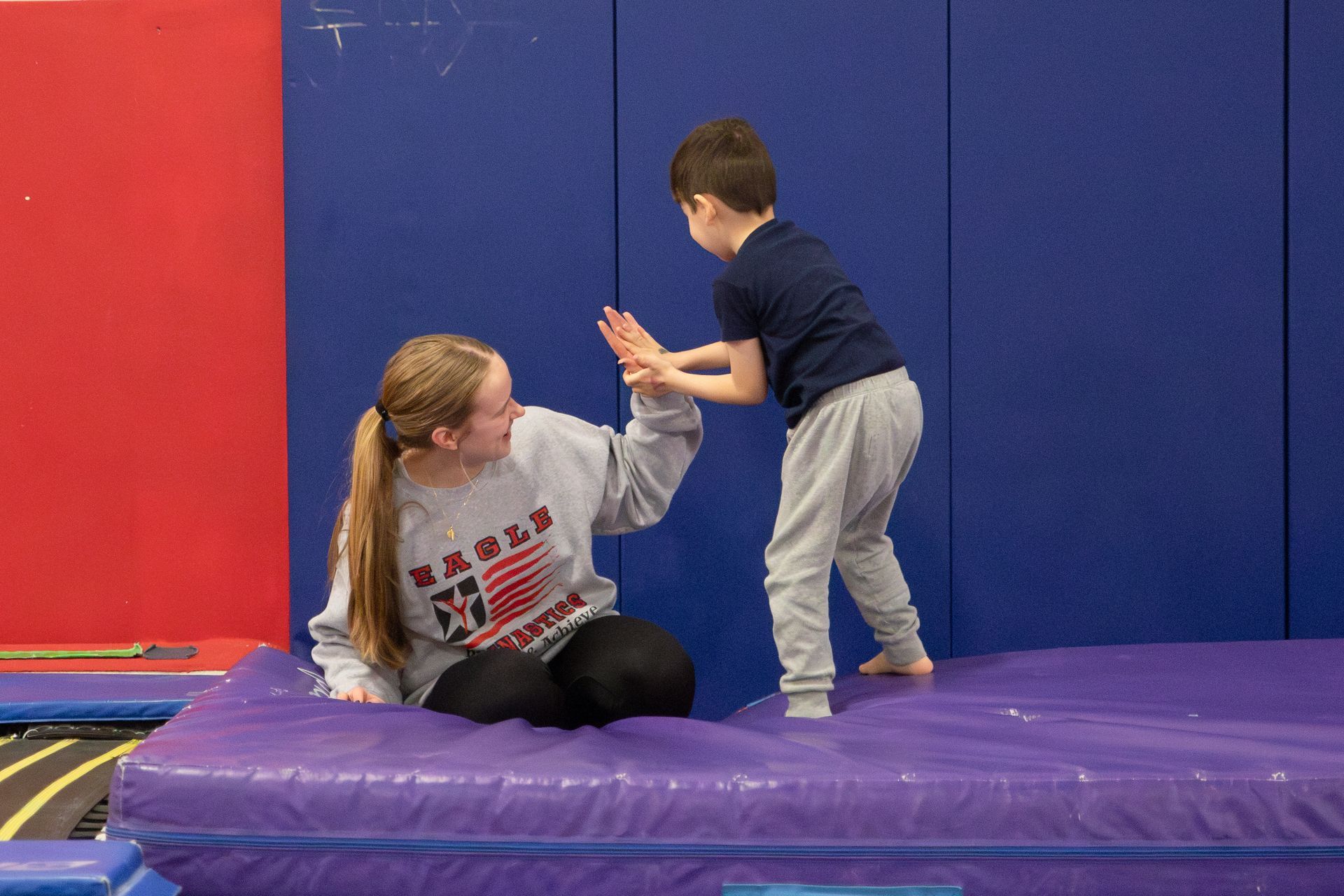 A female gymnast is doing a flip on a trampoline.