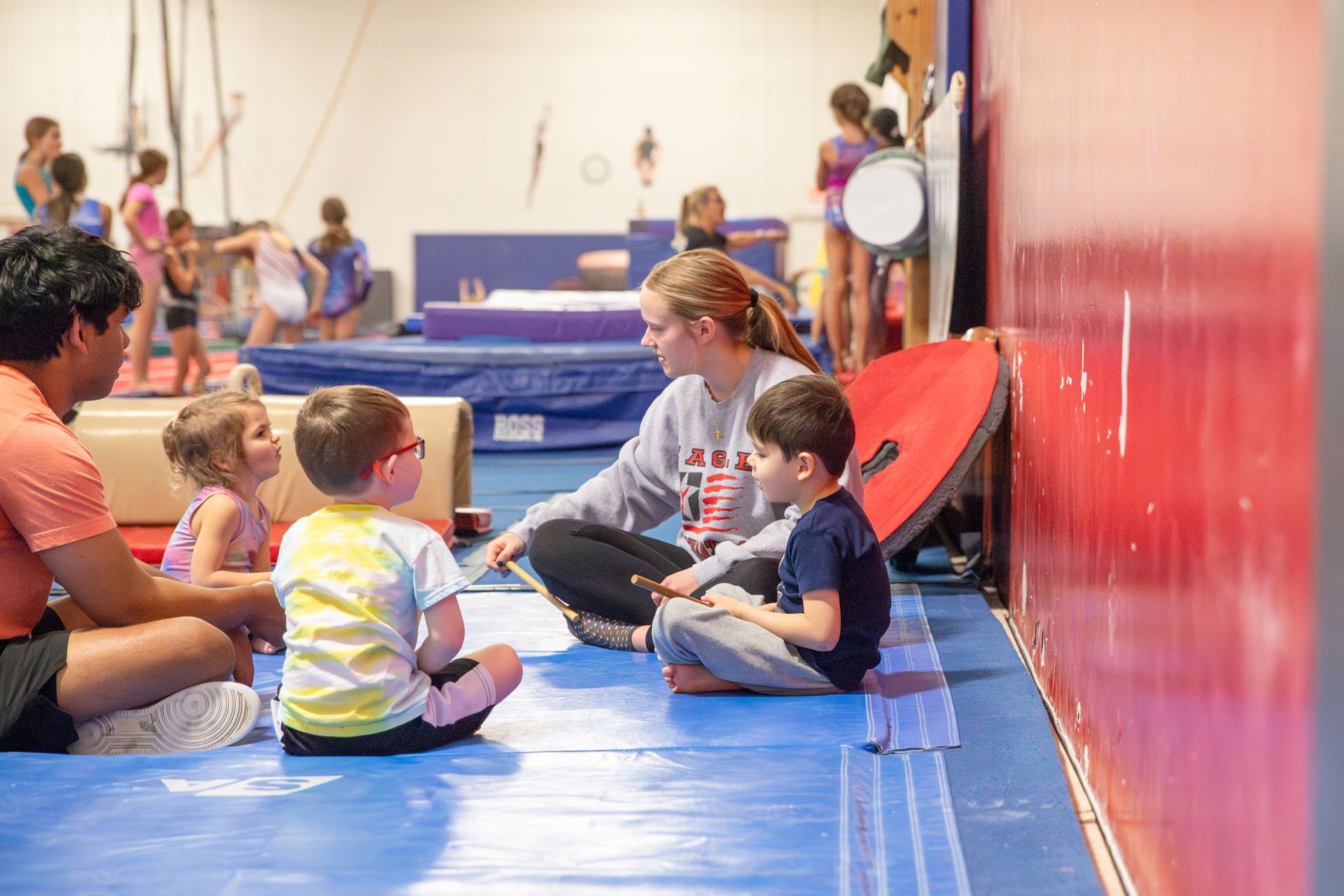 Two female gymnasts are laughing together while standing next to each other in a gym.