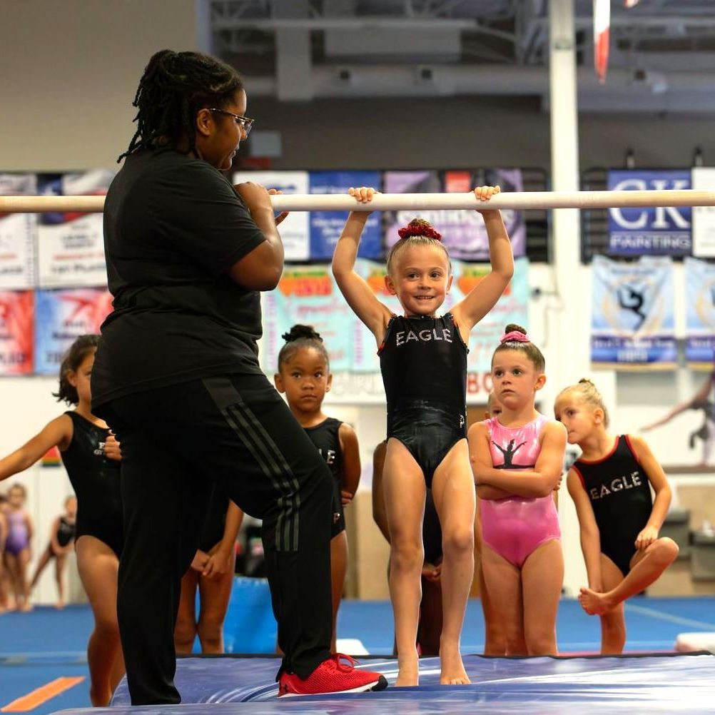 A group of young girls in eagle leotards are doing gymnastics