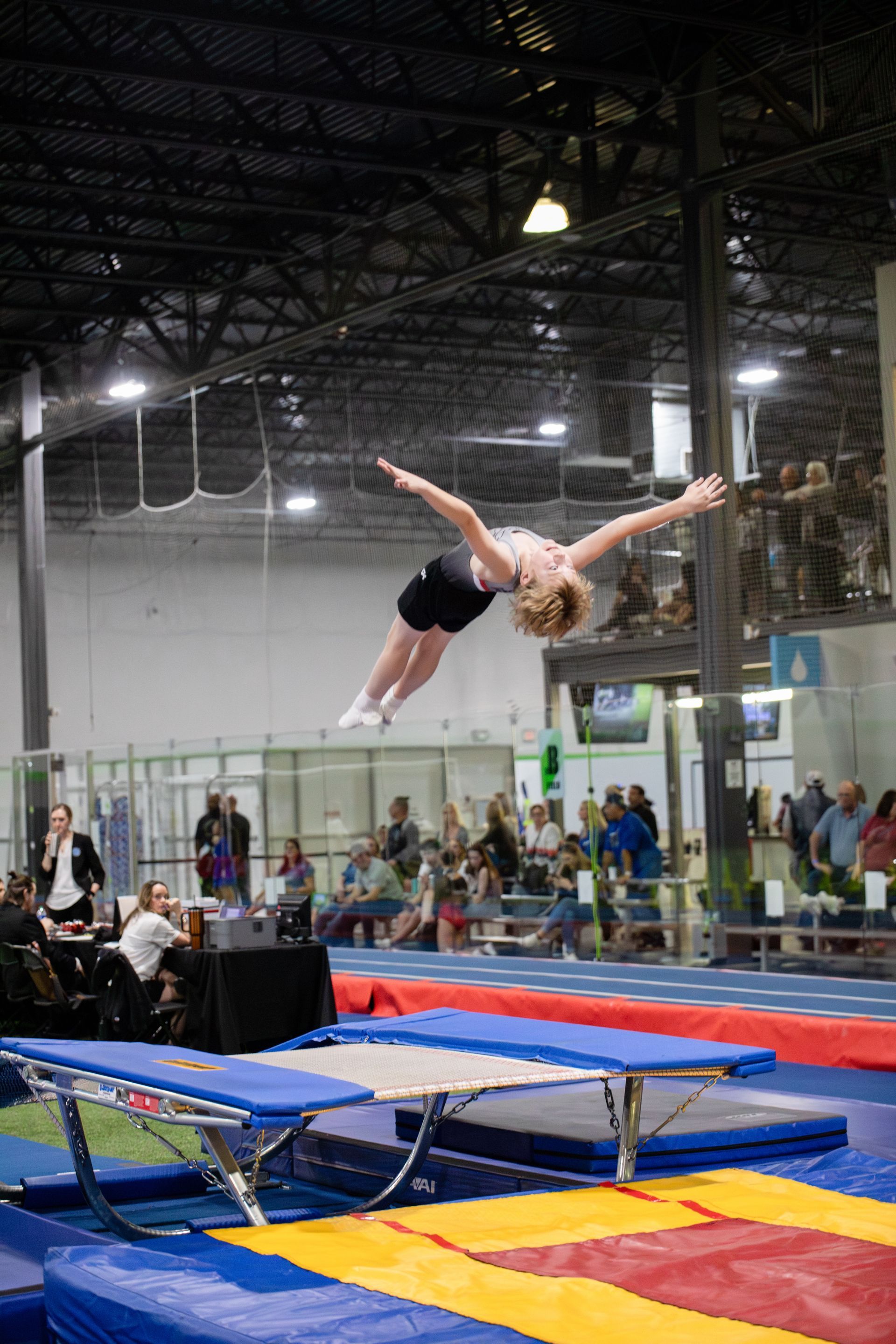 A woman is doing a trick on a trampoline in a gym.