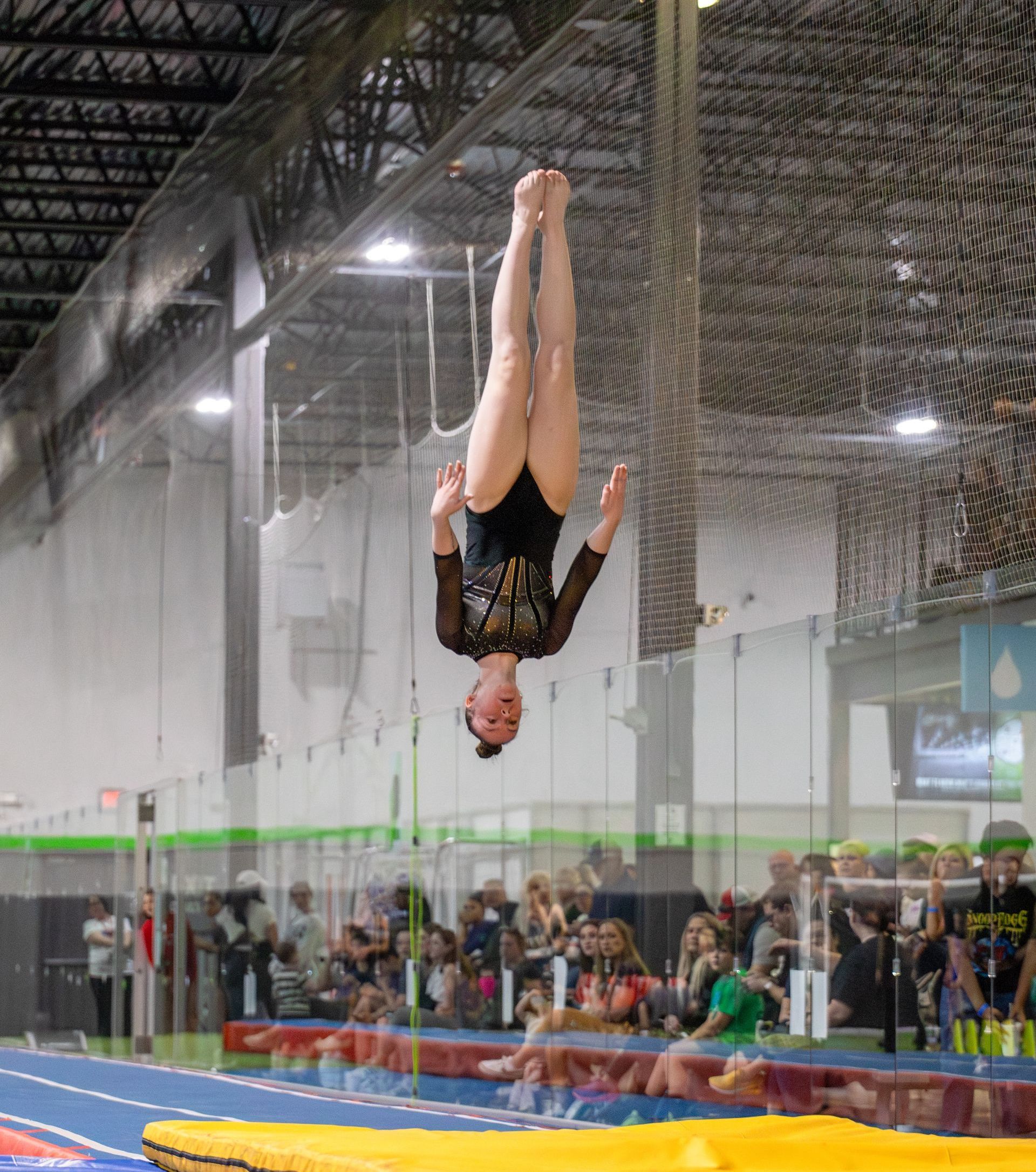 A woman is doing a handstand on a trampoline in a gym