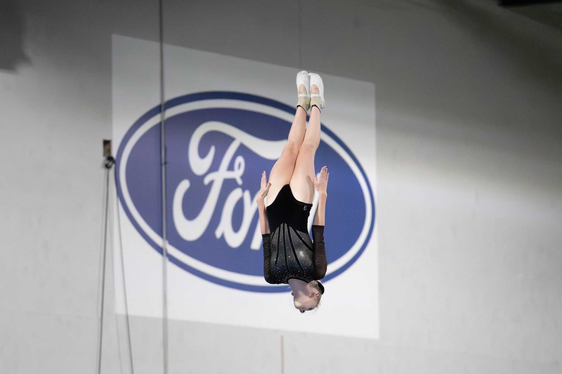 A woman is doing a handstand in front of a ford logo