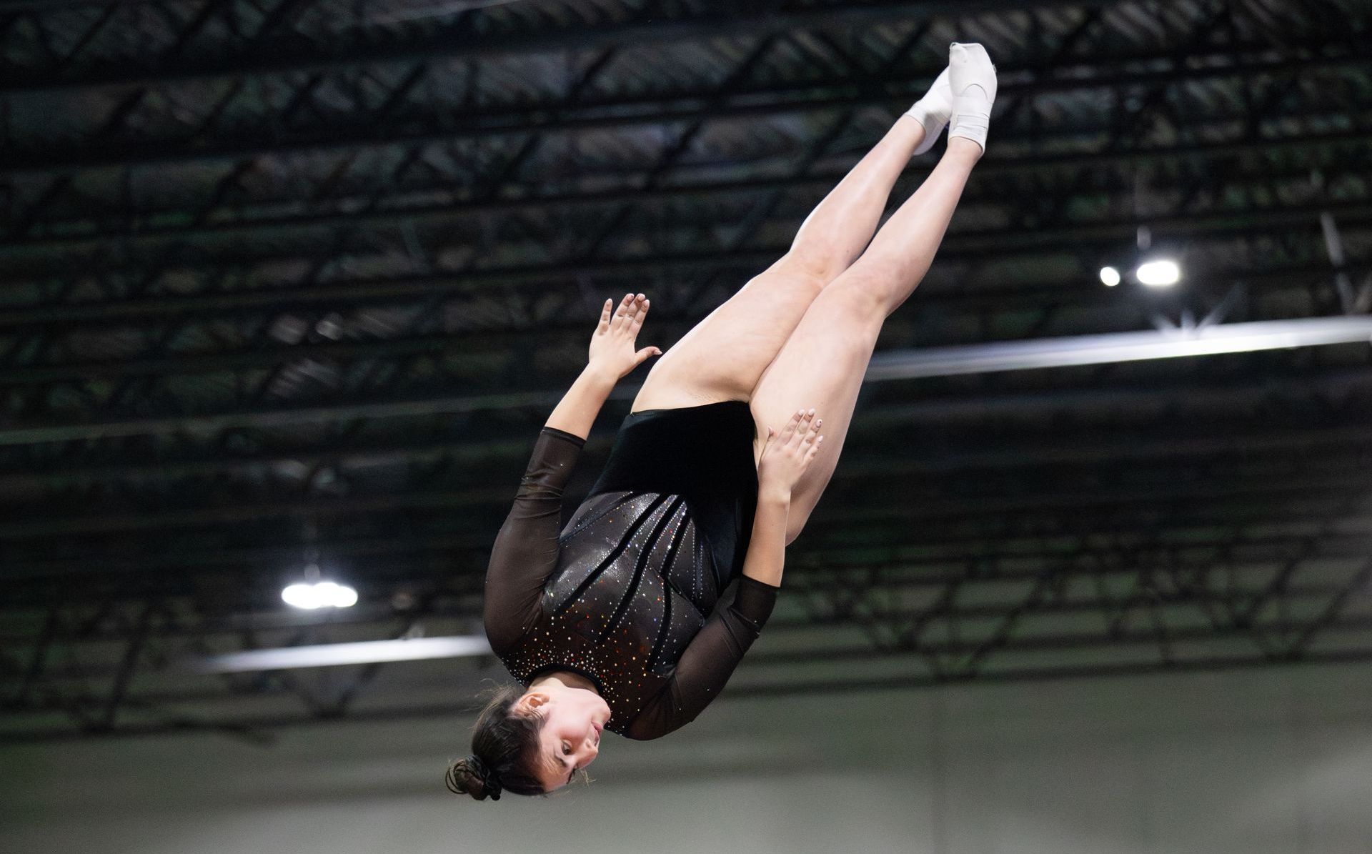 A female gymnast is doing a trick on a trampoline.