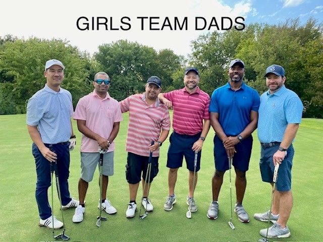 A group of men are standing on a golf course holding golf clubs.