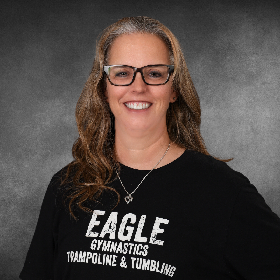 A woman wearing glasses and a black shirt that says eagle gymnastics trampoline and tumbling