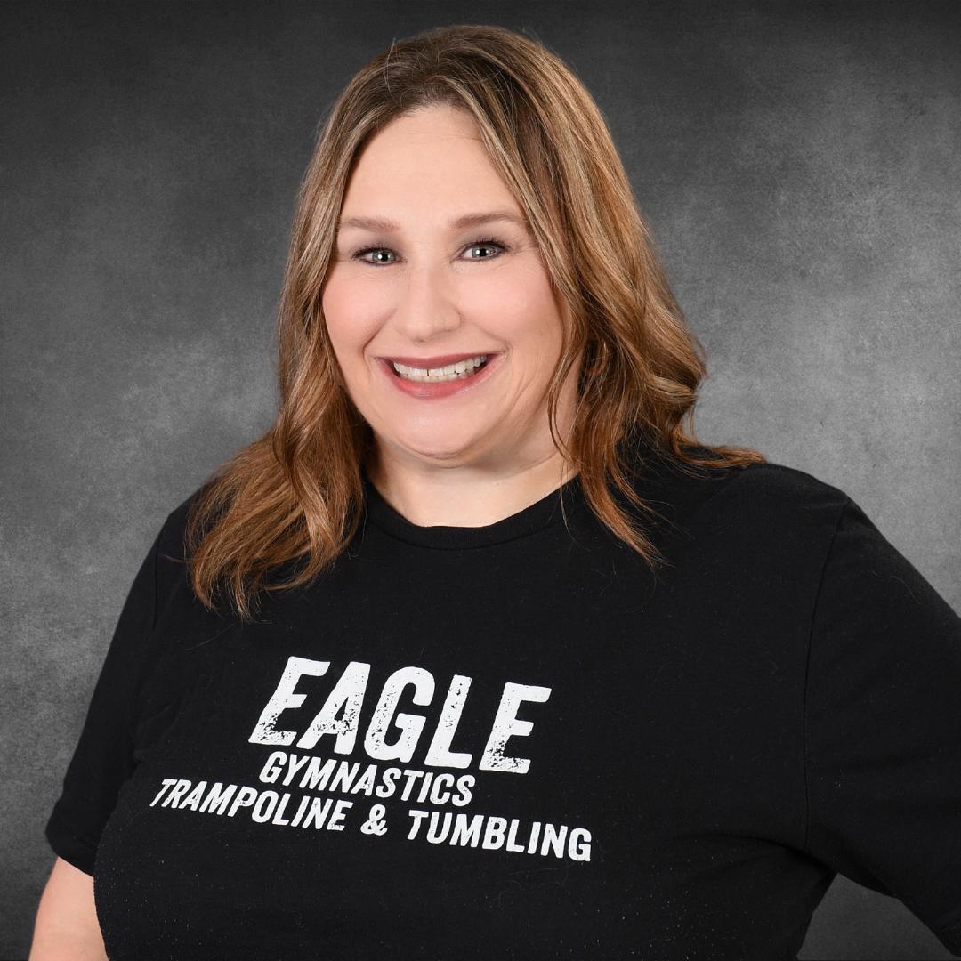 A woman wearing a black shirt that says eagle gymnastics trampoline and tumbling