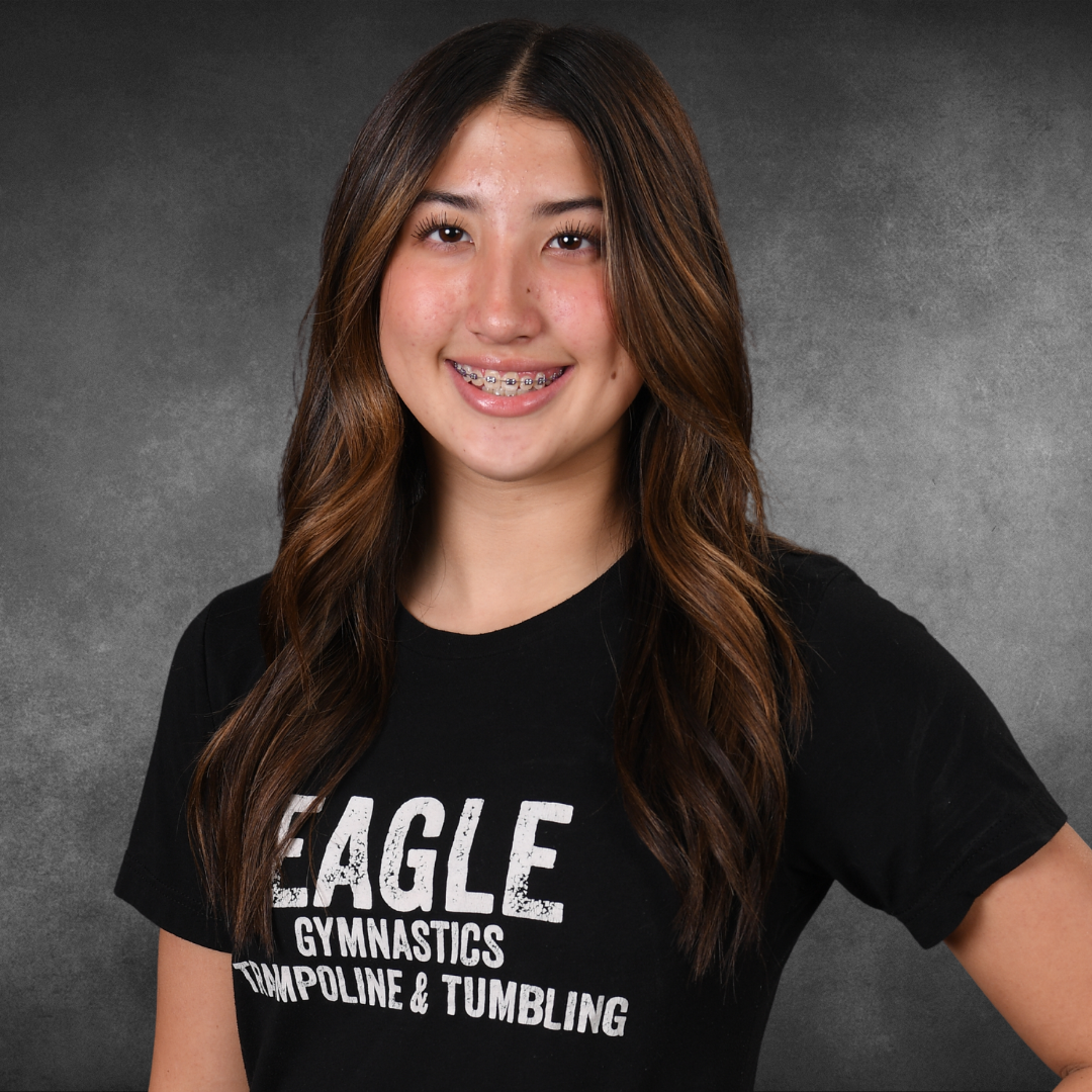 A girl wearing a black shirt that says eagle gymnastics trampoline and tumbling
