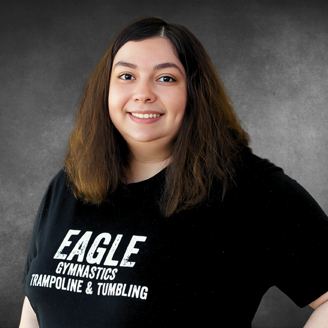 A woman wearing a black shirt that says eagle gymnastics trampoline and tumbling