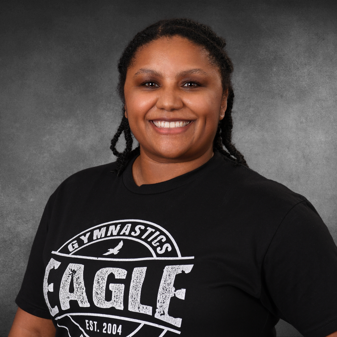 A woman wearing glasses and a black shirt that says eagle gymnastics trampoline and tumbling