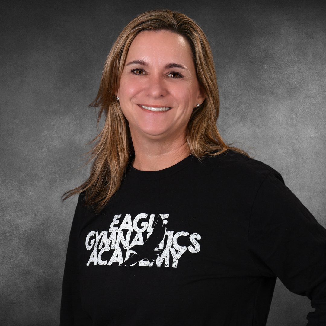 A woman wearing a black shirt that says each gymnastics academy