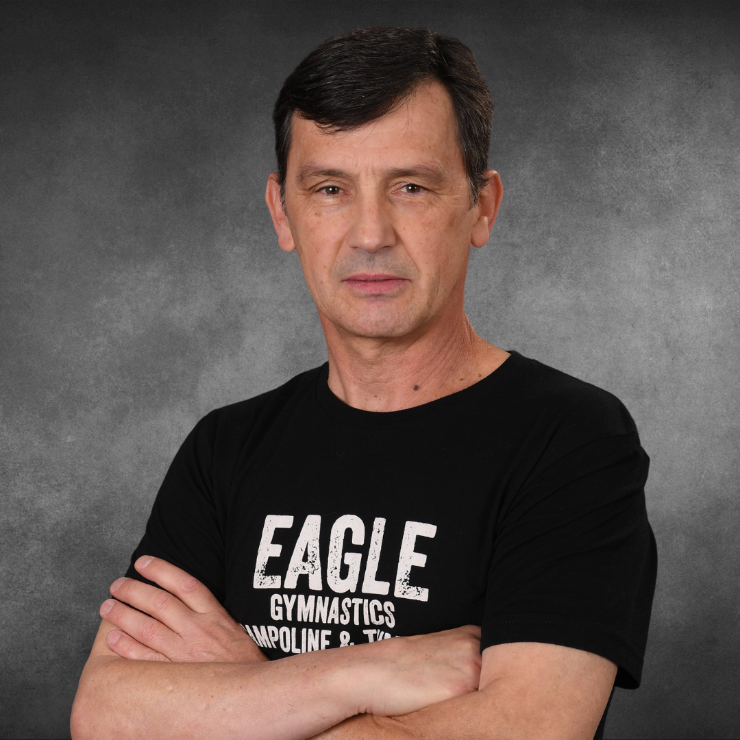 A man wearing a black eagle gymnastics shirt with his arms crossed