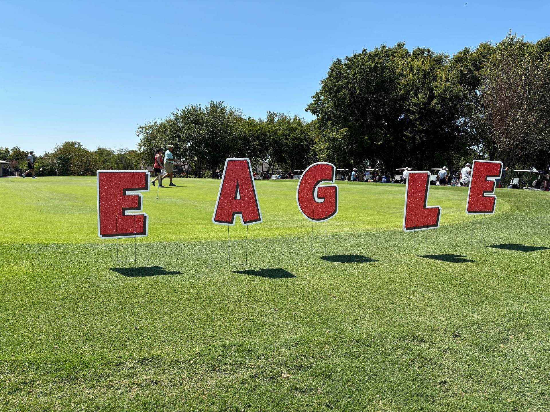 The word eagle is written in red letters on a grassy field.
