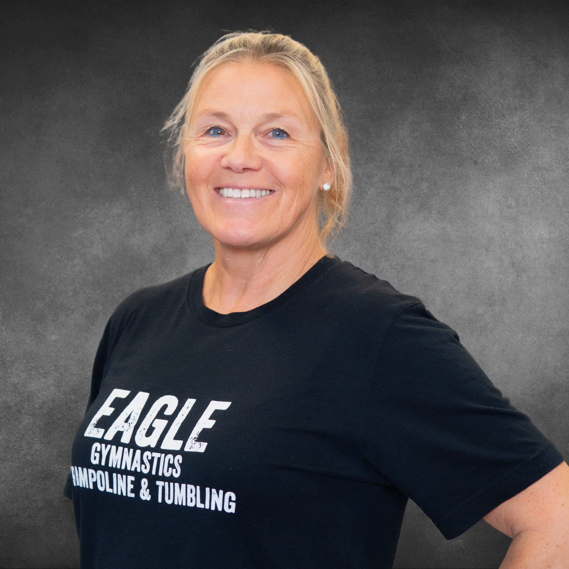 A woman wearing a black eagle gymnastics trampoline and tumbling shirt