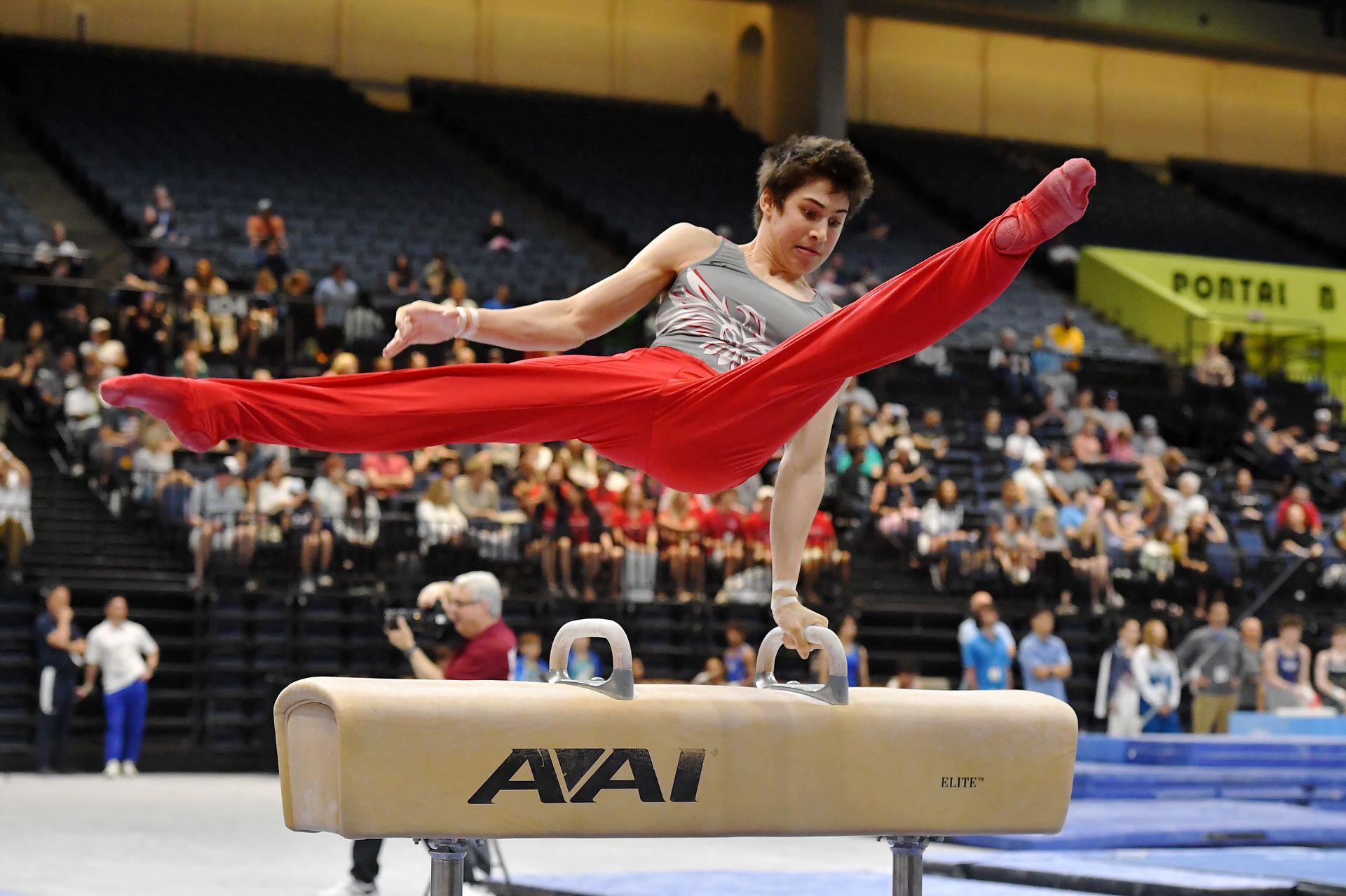 A man is doing a split on an aai pommel horse