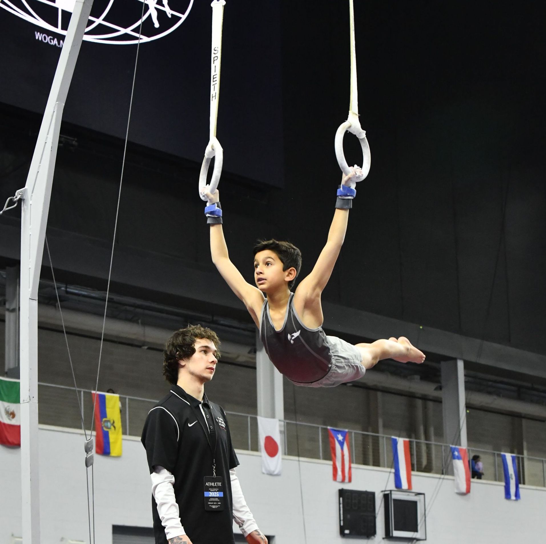 Two female gymnasts are laughing together while standing next to each other in a gym.
