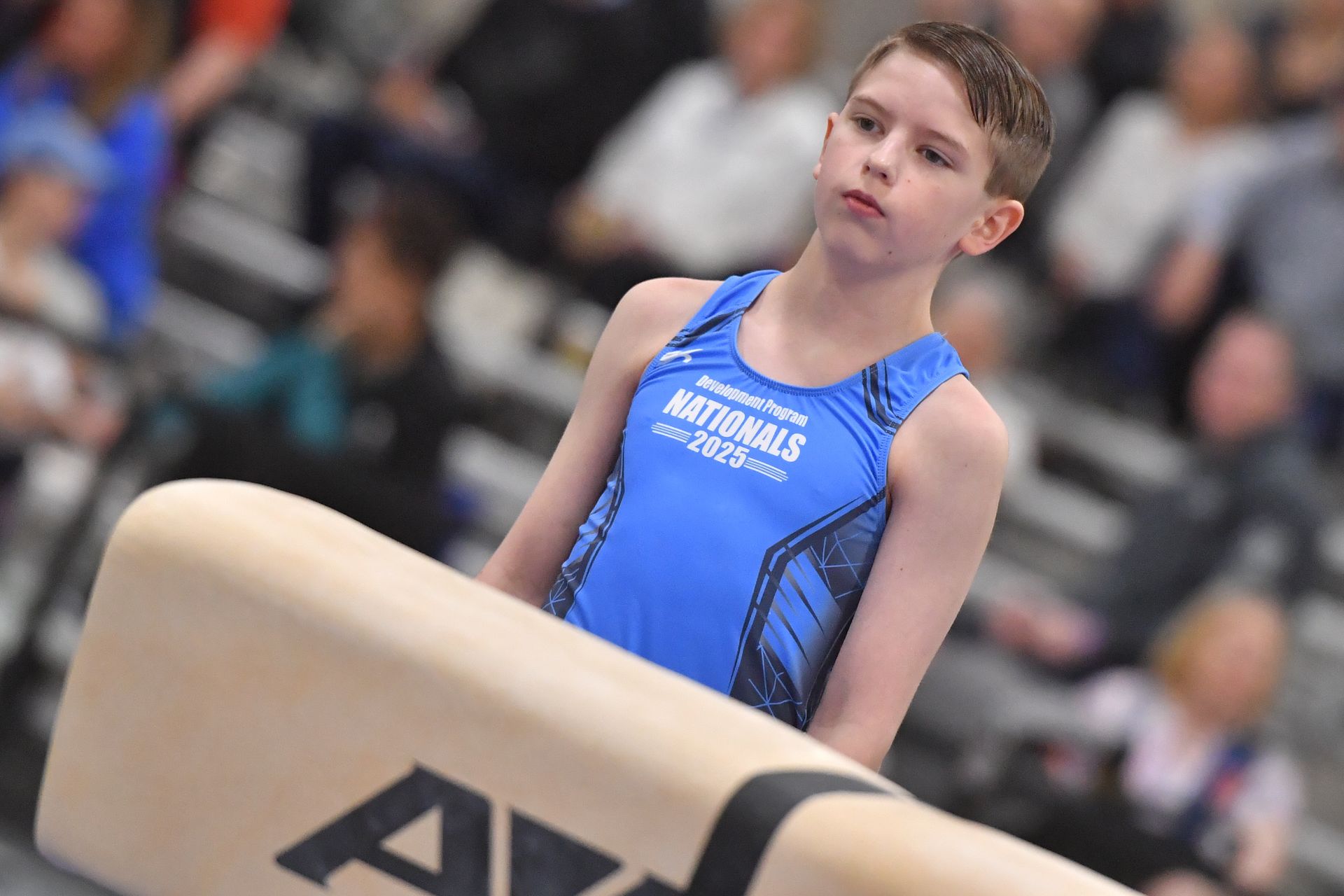 A man is doing a split on an aai pommel horse