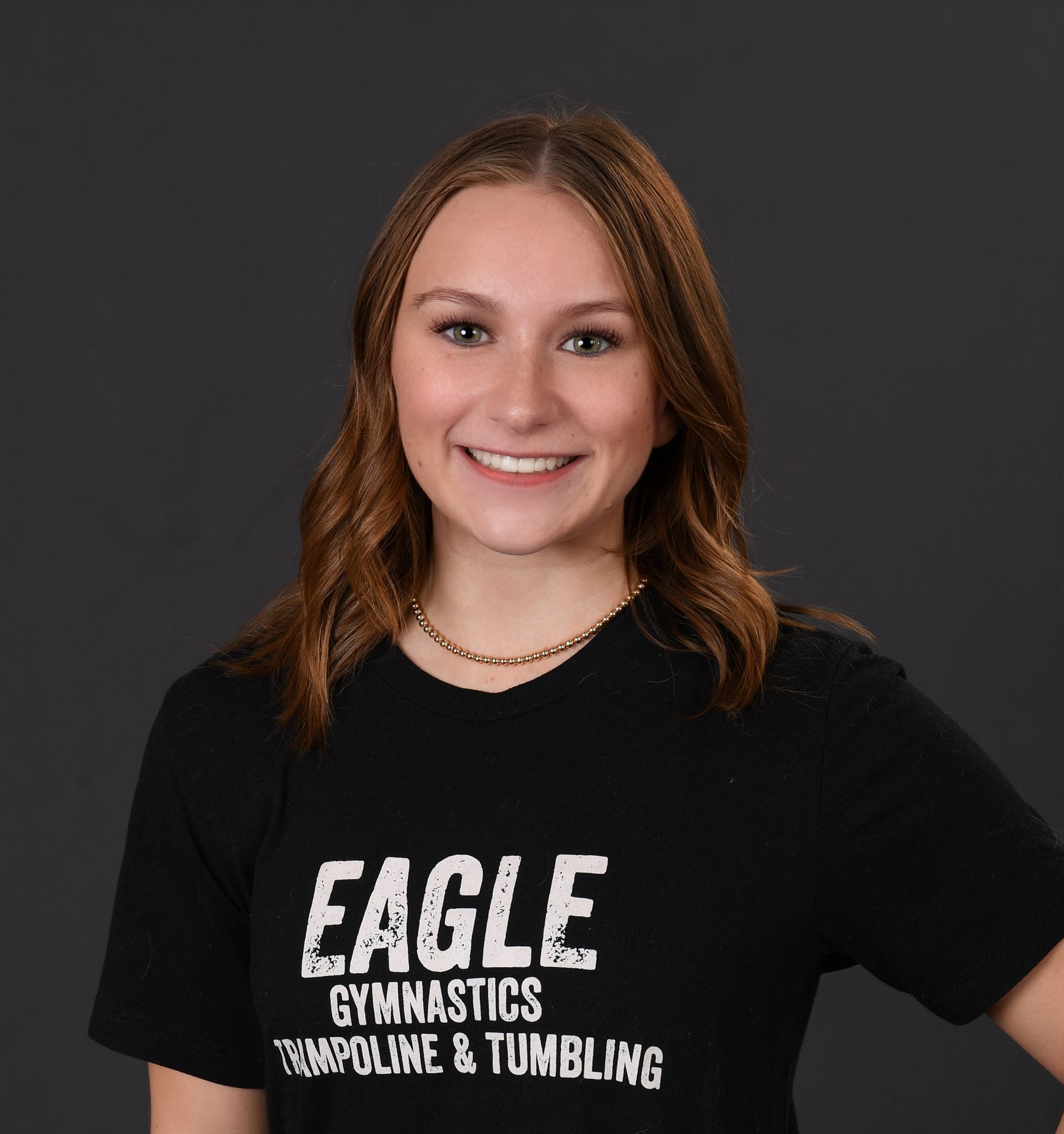 A young woman wearing a black eagle gymnastics trampoline and tumbling shirt