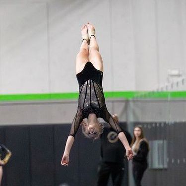 A female gymnast is doing a handstand in a gym.