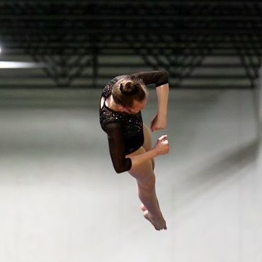 A female gymnast is doing a trick on a trampoline.