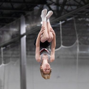 A young boy is doing a handstand on a trampoline.