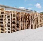 A row of wooden pallets stacked on top of each other in front of a building. Pallets of a student from the simplest biz