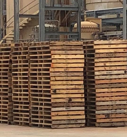 A bunch of wooden pallets are stacked on top of each other that need recycling 