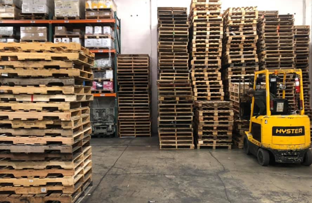 Stacks of used wooden pallets ready for pickup, representing recurring inventory in the pallet recycling business