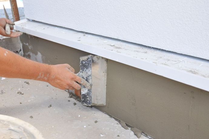 A person is using a spatula to plaster a wall.