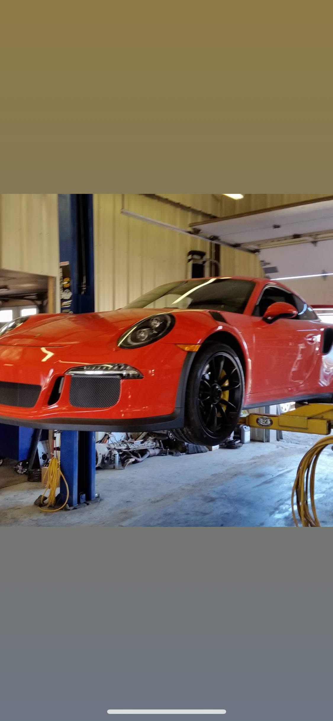 Orange Porsche 911 on a lift in a garage.