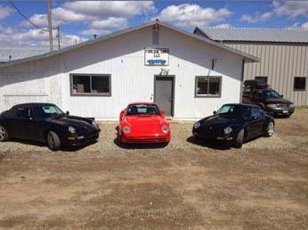 Three Porsches parked in front of a building, a red one between two black ones.