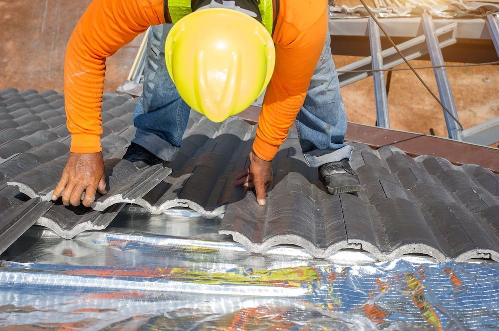 A Man Wearing a Hard Hat is Working on a Roof — Roof Restoration Masters In Tuggerah, NSW