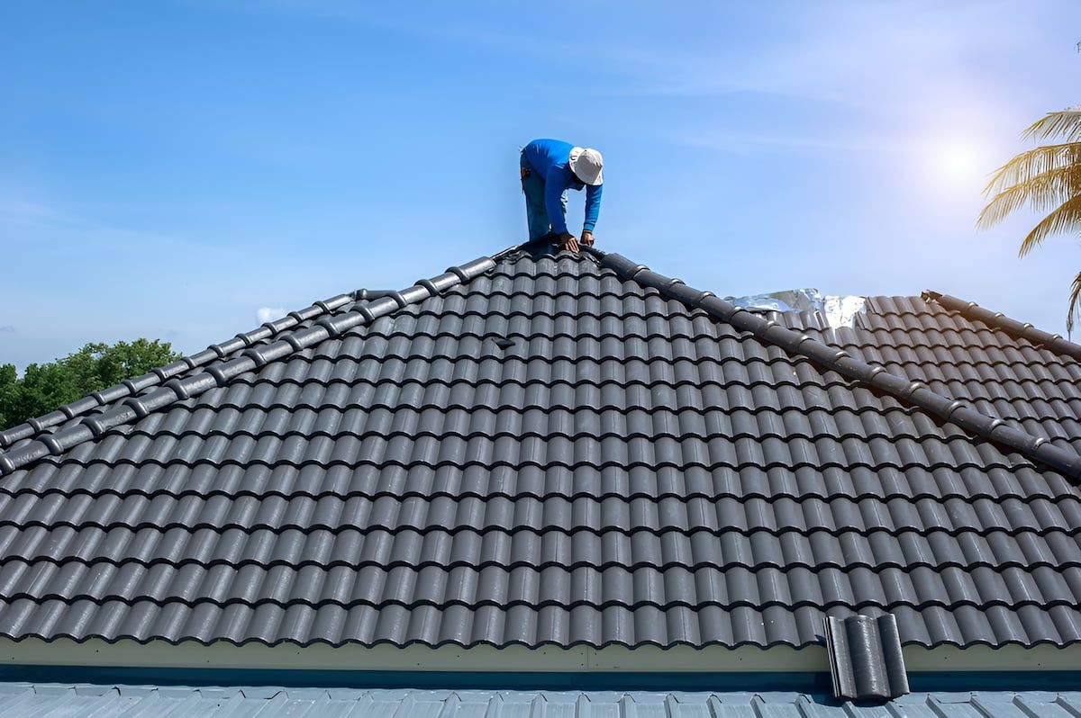 A Man is Working on the Roof of a House — Roof Restoration Masters In Gorokan, NSW
