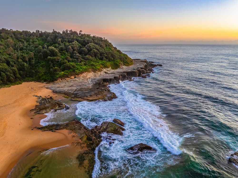 An Aerial View of a Beach With Waves Crashing Against the Rocks — Roof Restoration Masters In Wamberal, NSW