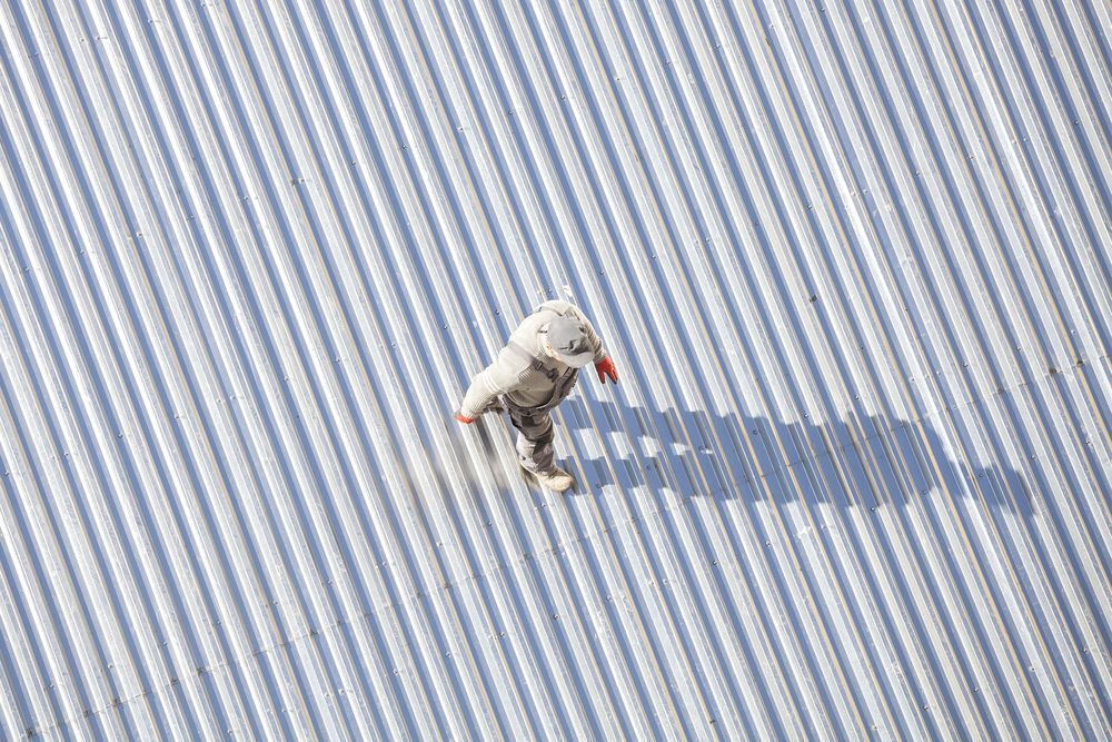 An Aerial View of a Person Standing on a Striped Roof — Roof Restoration Masters In Valentine, NSW