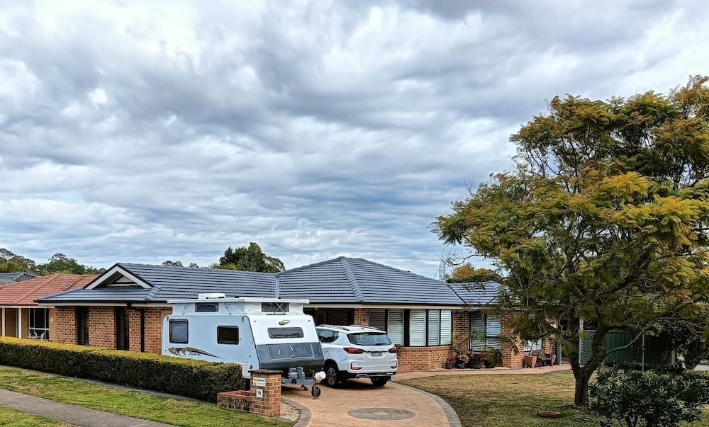 A House With a Trailer Parked in Front of It — Roof Restoration Masters In Minmi, NSW