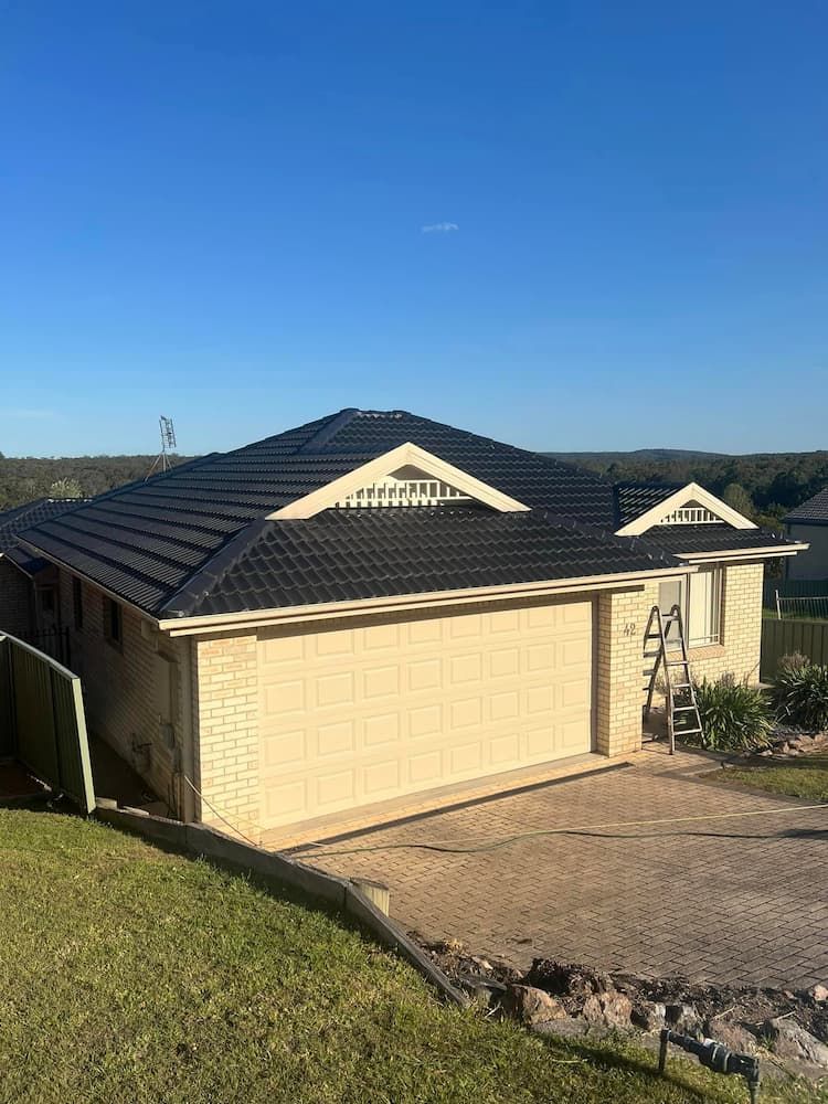 A House With a Black Roof and a Large Garage Door — Roof Restoration Masters In Maryland, NSW