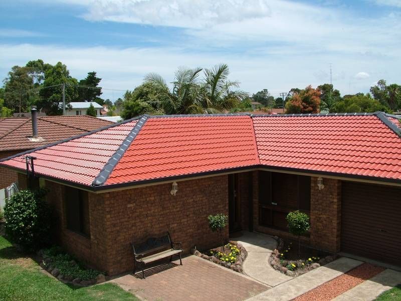 A Brick House With a Red Tiled Roof — Roof Restoration Masters In Morisset Park, NSW