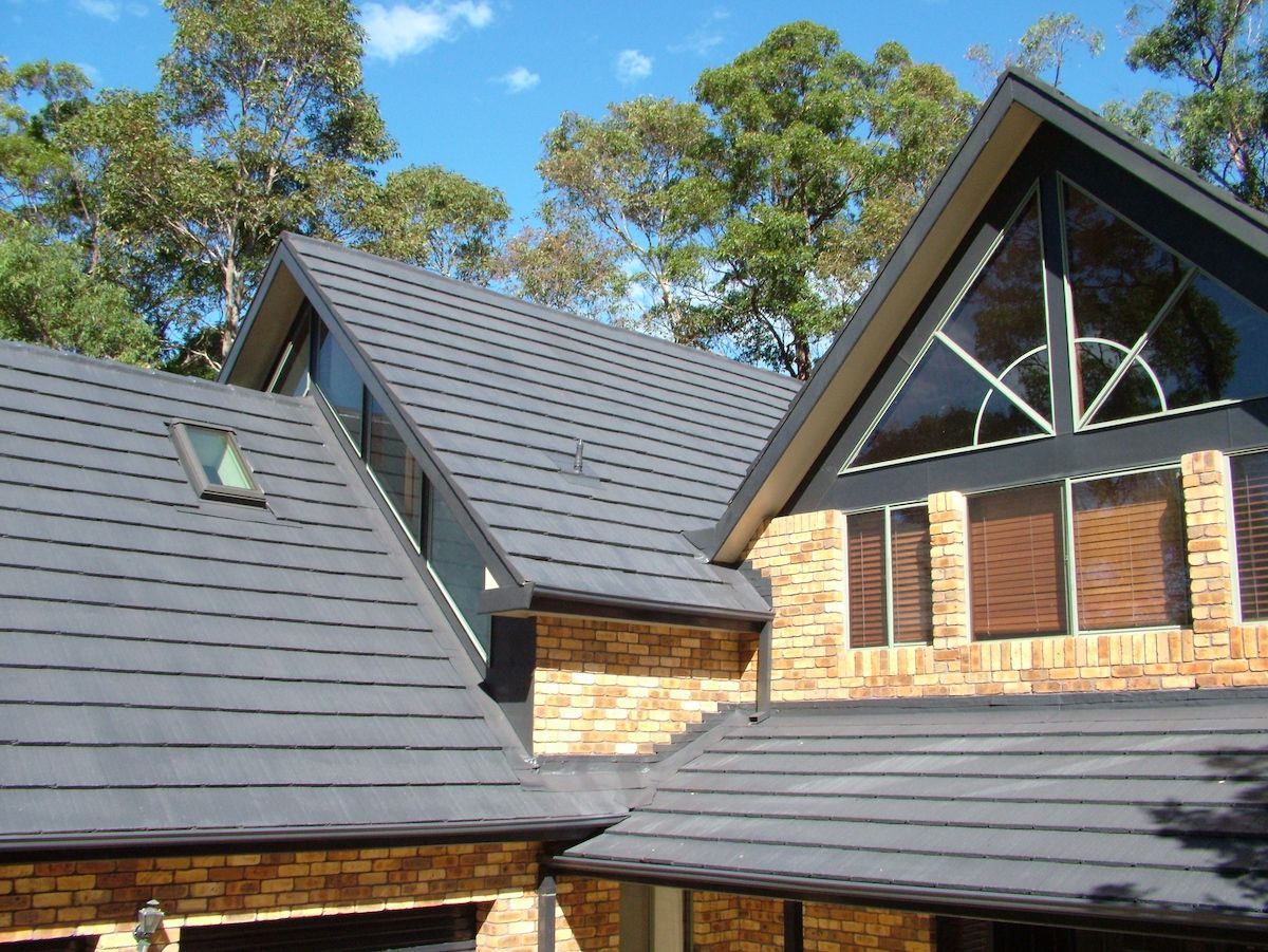 Two men are working on the roof of a house — Roof Restoration Masters in Morisset, NSW